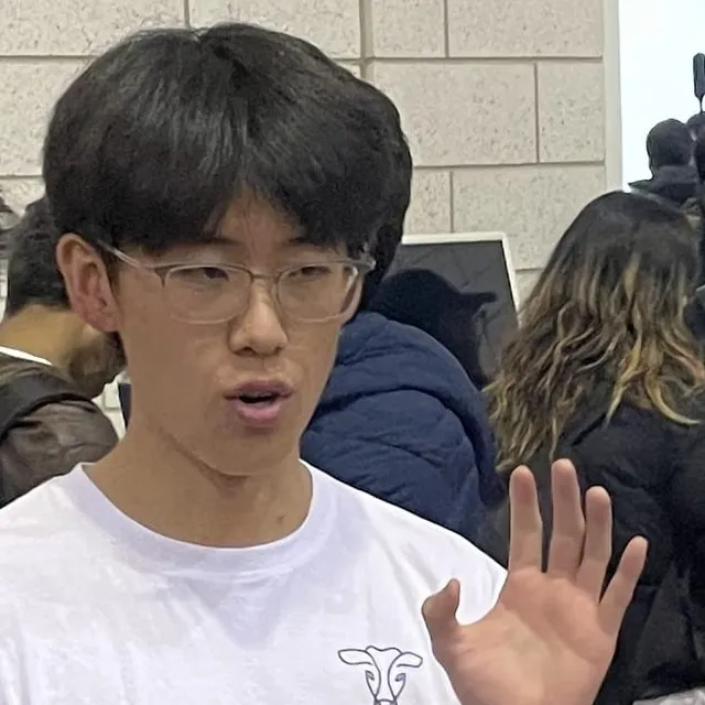 Zhaojin Chu mid-sentence at TartanHacks, one hand raised, a coffee cup in the other
