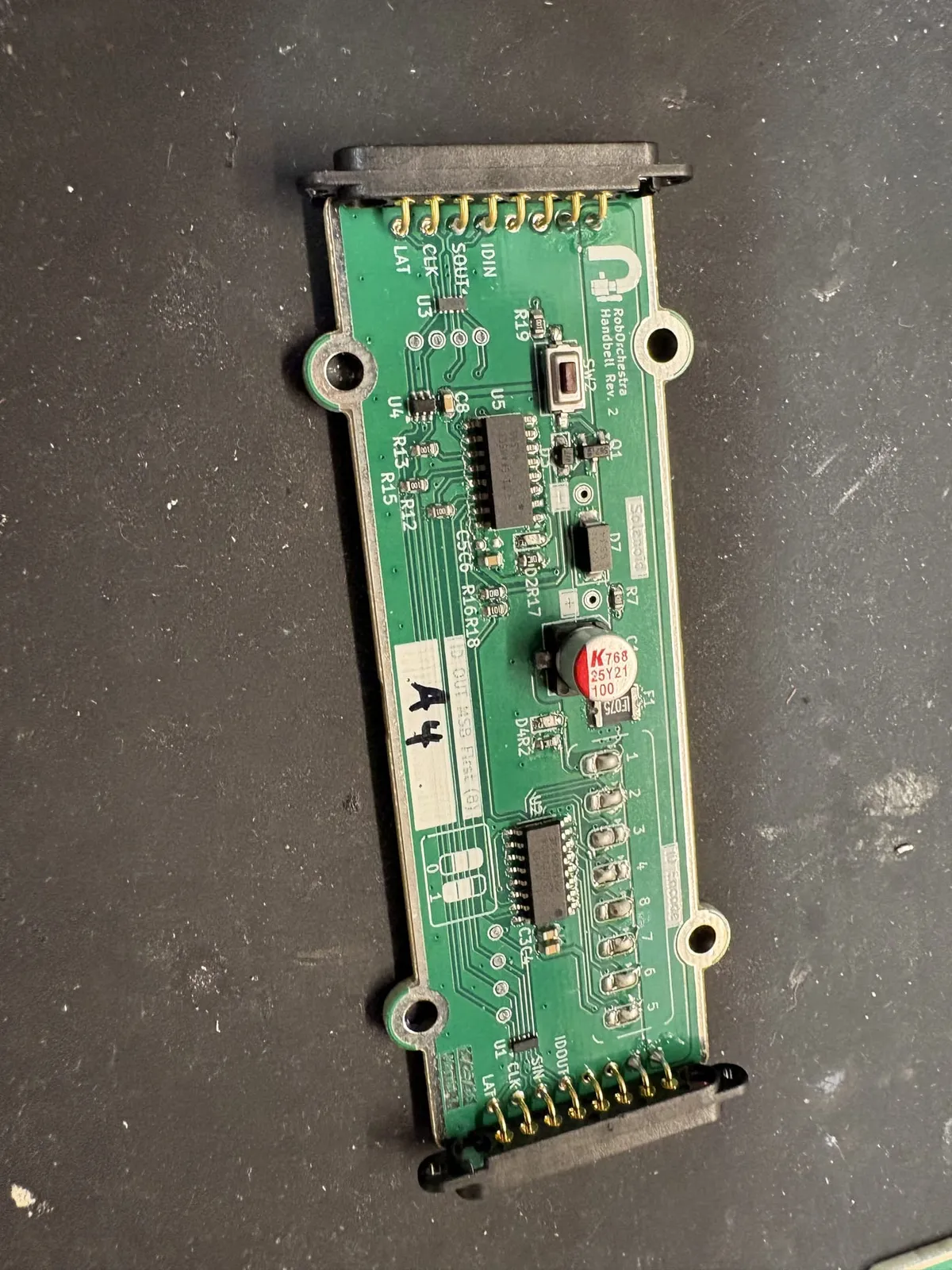 One RoboOrchestra handbell board, Rev. 2: a shift register, a solenoid driver, a DIP switch for the board’s ID and an eight-pin connector at each end, with A4 written on its label